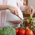 Schwangere Frau bereitet sich einen Salat zu